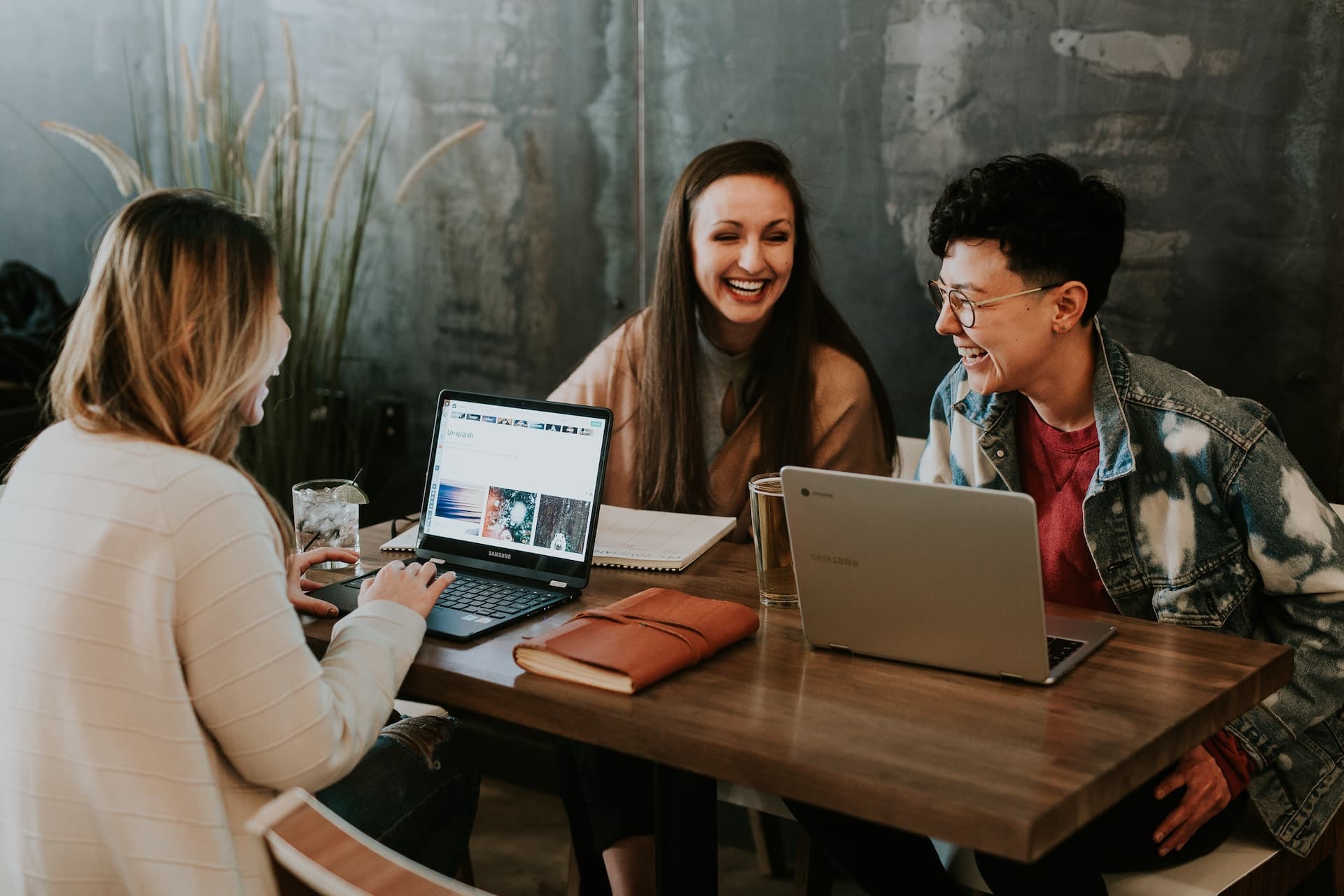 Three women sitting on a desk and laughing